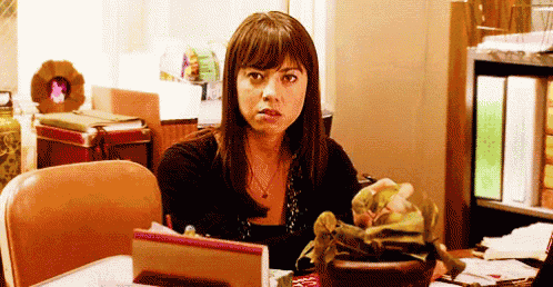 a woman is sitting at a desk with a plant in a pot .