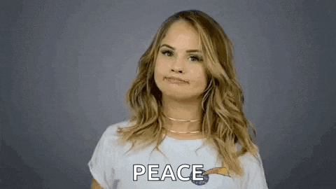 a woman in a white t-shirt is giving a peace sign .