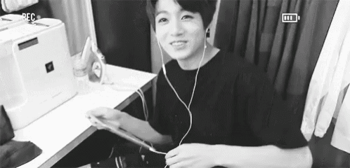 a black and white photo of a young man wearing headphones while playing a video game .
