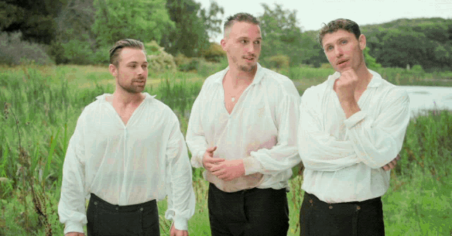 three men wearing white shirts and black pants are standing in a field