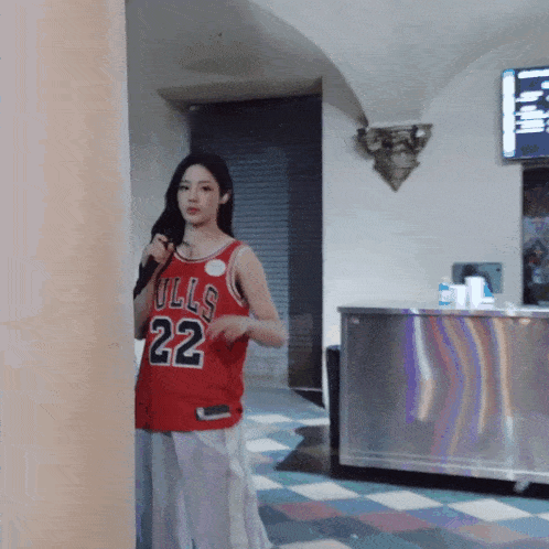 a woman in a red bulls jersey stands in a hallway