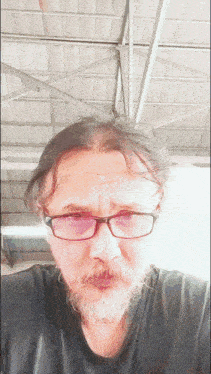 a man with glasses and a beard is taking a selfie