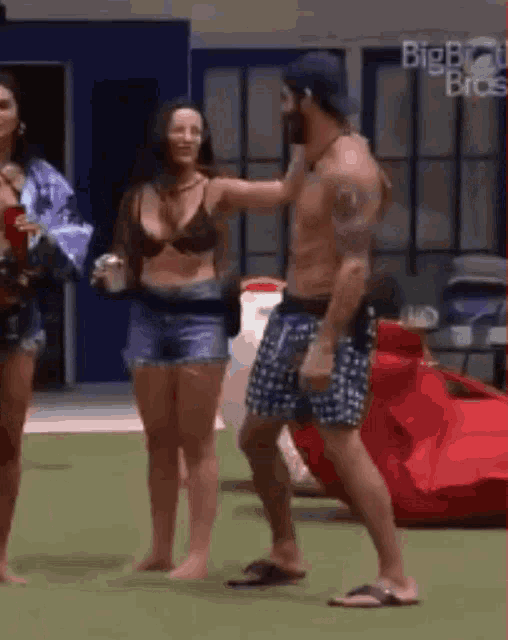 a man is standing next to a woman in a bikini on a lawn .