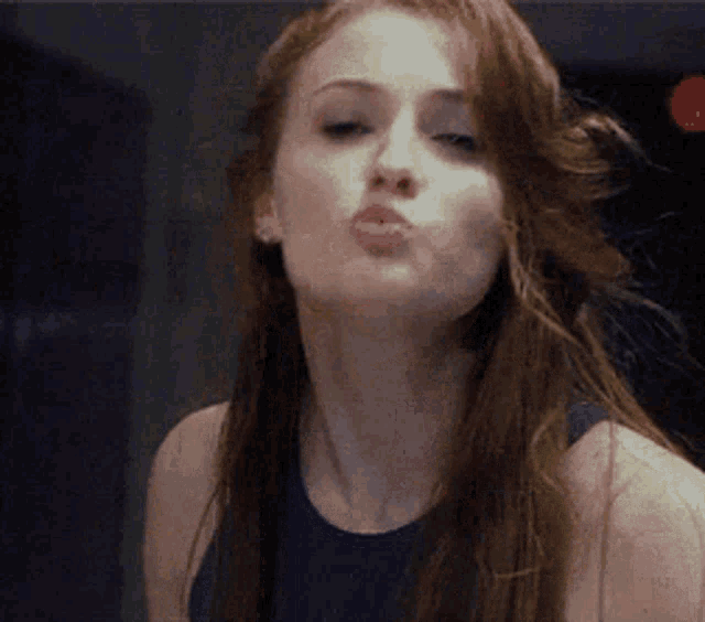 a woman with long hair is blowing a kiss at the camera .