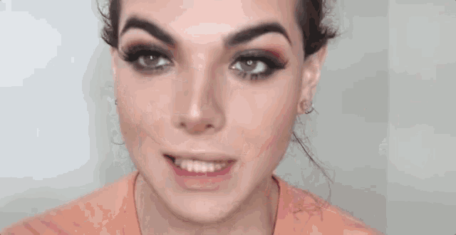 a woman with long red nails is touching her eyebrows and making a face .