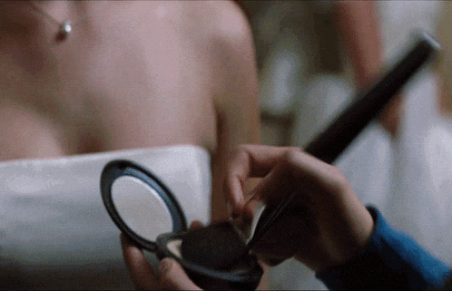a woman in a white dress is getting her makeup done