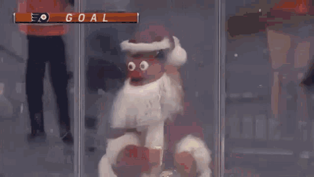 a puppet wearing a santa hat is behind a glass door