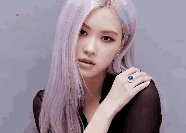 a woman with purple hair is wearing a ring on her left hand
