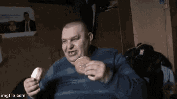a man in a blue sweater is eating a donut .