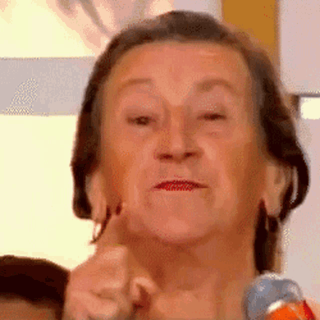 a close up of an elderly woman 's face with a microphone in front of her