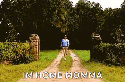 a man is walking down a dirt road with the words im home momma written on the side .