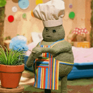 a stuffed animal wearing a chef 's hat and apron holds a toothpick