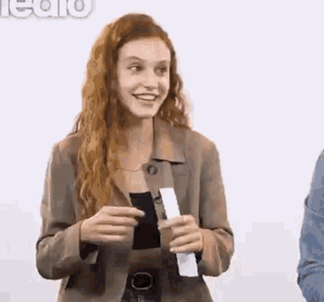 a woman with red hair is holding a piece of paper in her hands and smiling .