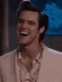 a man in a suit and shirt is laughing and smiling .