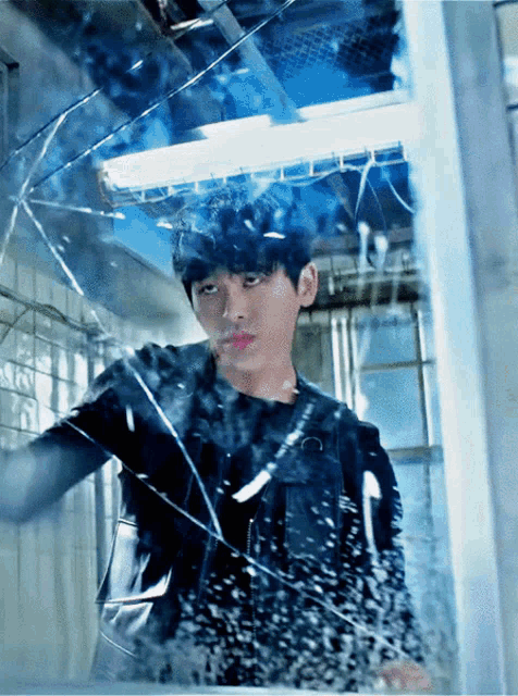 a young man is standing in front of a broken glass window