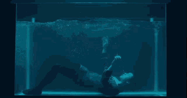 a person in a blue jacket is laying in a tank of blue water