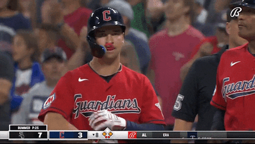 a baseball player wearing a red uniform that says guardians on it