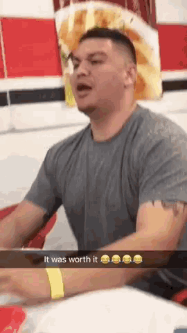 a man in a gray shirt is sitting at a table with a snapchat that says it was worth it