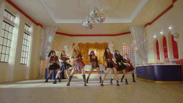a group of girls are dancing in a room with a disco ball hanging from the ceiling