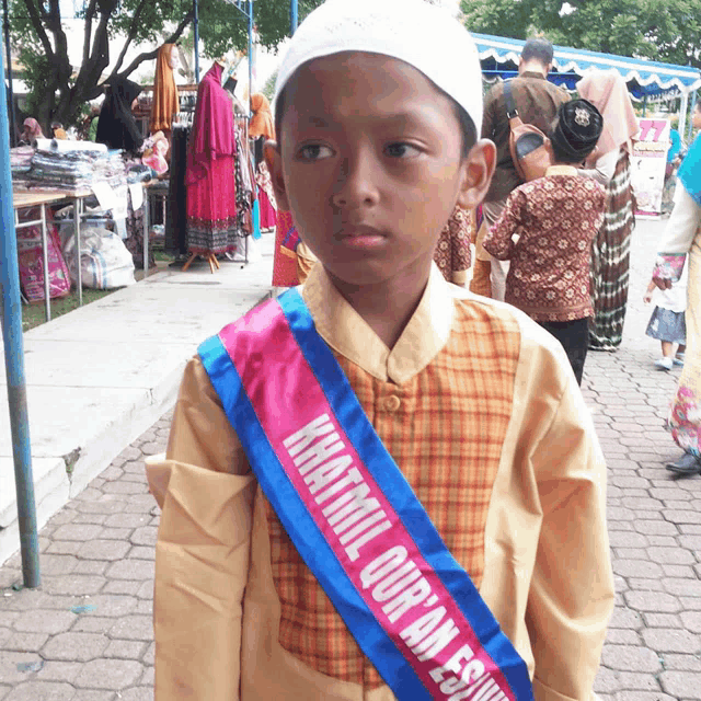 a boy wearing a sash that says khatmil quran