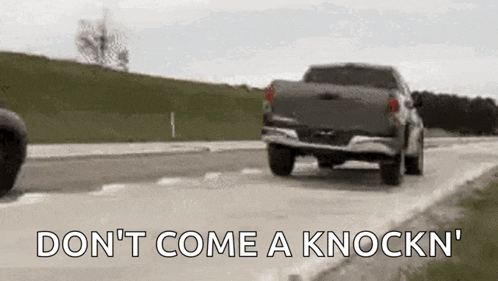 a truck is driving down a road with the words `` do n't come a knockn '' written on the side .