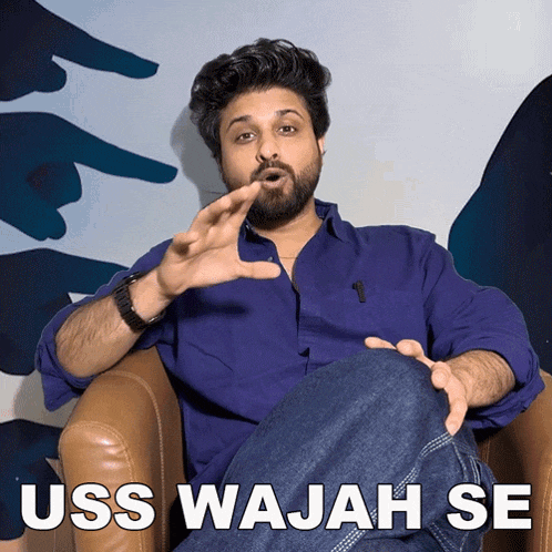 a man in a blue shirt is sitting in a chair with uss wajah se written in white