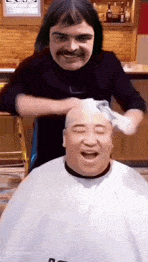 a man with a mustache is getting his hair cut by a barber .