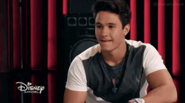 a young man is sitting in front of a disney channel logo