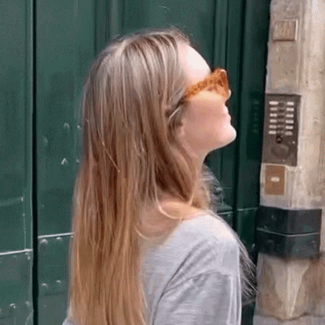 the woman is wearing sunglasses and a grey shirt .