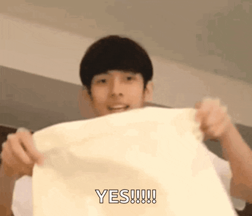a young man is holding a piece of paper in his hands and says yes .
