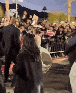 a woman in a white dress stands in front of a crowd of people
