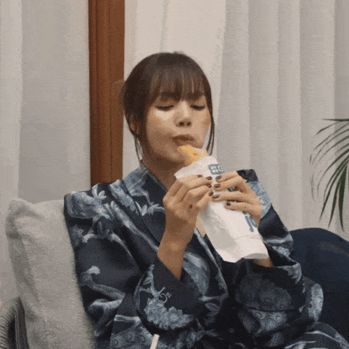 a woman sitting on a couch eating a sandwich with a sticker on it that says ' fc '