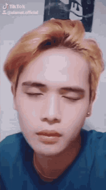 a young man with blonde hair is making a funny face .