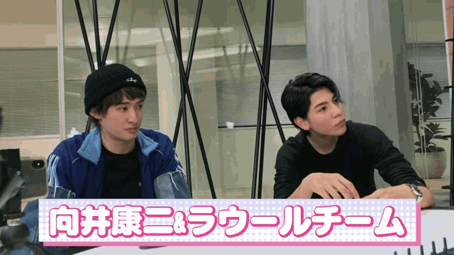 two men are sitting in front of a sign that says ' a & a '