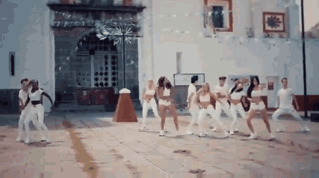 a group of people are dancing on a street in front of a church .