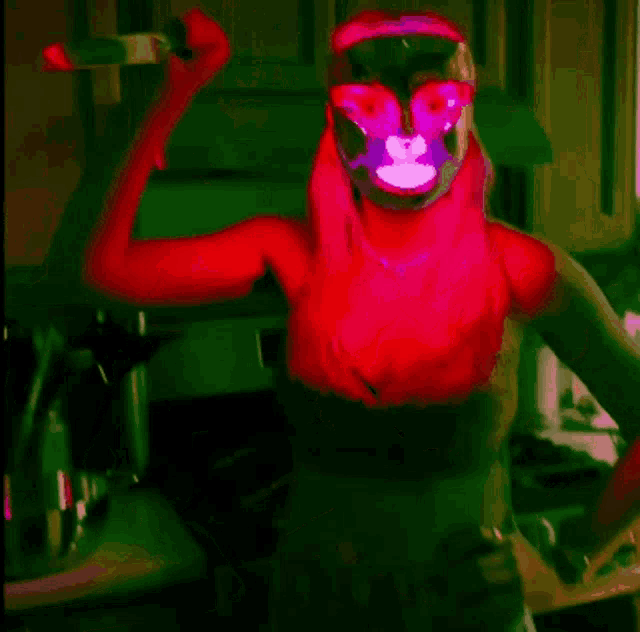 a woman with a mask on her face is flexing her muscles in a kitchen