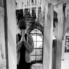 a black and white photo of a person praying in front of a mirror