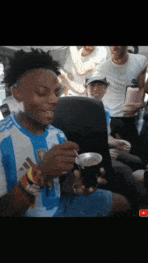 a man in a blue and white adidas shirt holds a cup