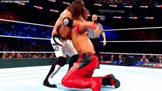 two wrestlers are fighting in a wrestling ring with a referee watching .