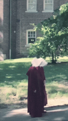 a woman in a red robe and white hat is walking down a street