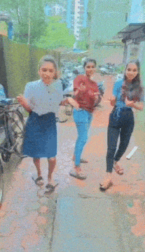a group of girls are standing on a sidewalk and one of them has a bottle of water in her hand