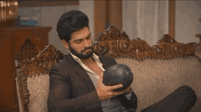 a man in a suit is sitting on a couch holding a black object