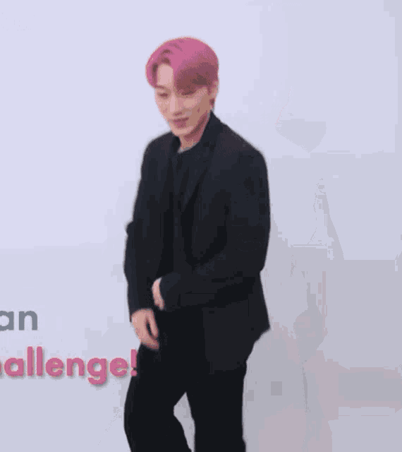 a young man with pink hair is wearing a black jacket and black pants and is dancing .