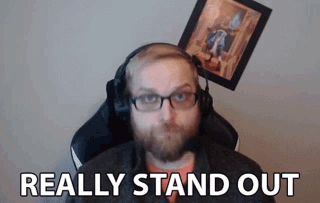 a man with glasses and headphones is sitting in a chair and says really stand out .