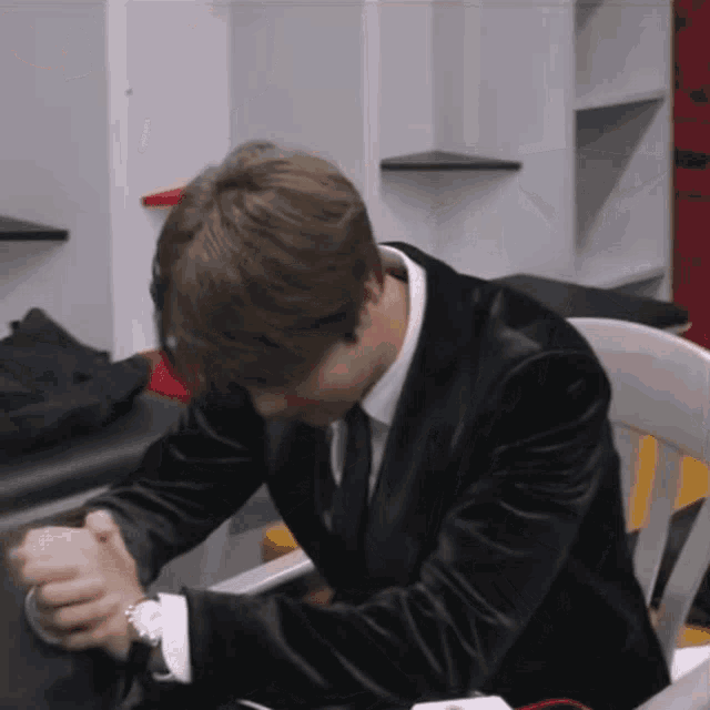 a man in a suit sits in a chair with his head down