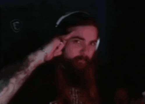 a man with a beard is wearing headphones and looking at the camera