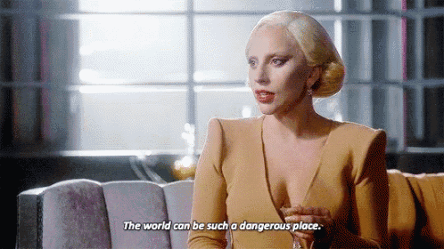 a woman is sitting on a couch holding a glass of wine and saying the world can be such a dangerous place