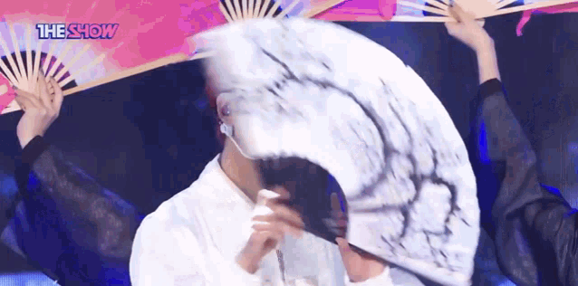a person is holding a fan in front of their face .