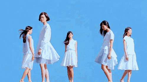 a group of young women in white dresses are walking in a row against a blue sky .
