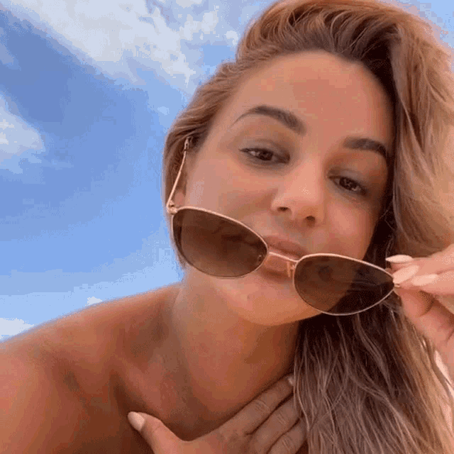 a woman without a shirt is wearing sunglasses and making a funny face